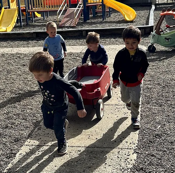 kids pulling a red wagon at the playground