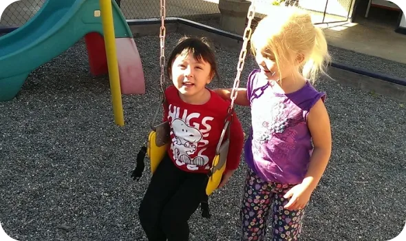 two kids playing on a swing