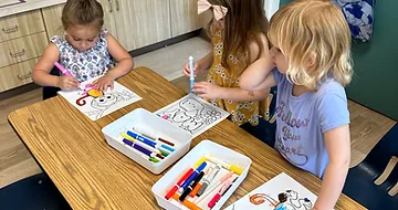 Kids sitting at a table drawing.