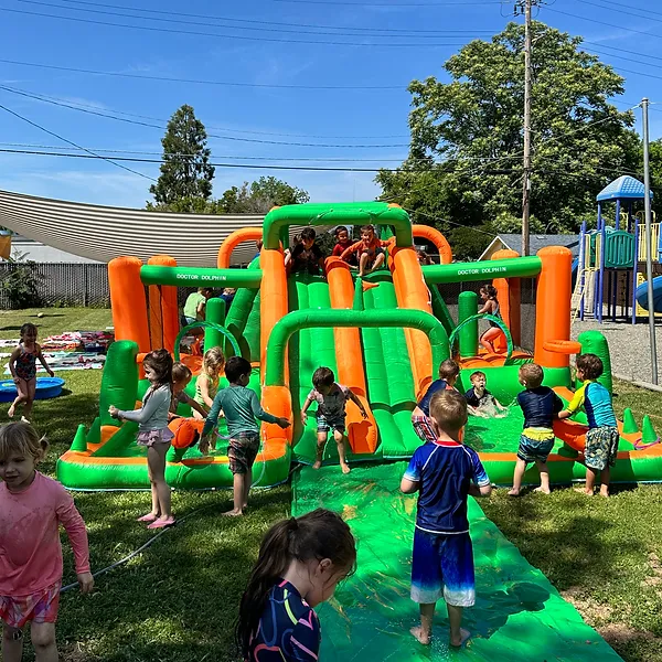 Many kids playing on water slide.